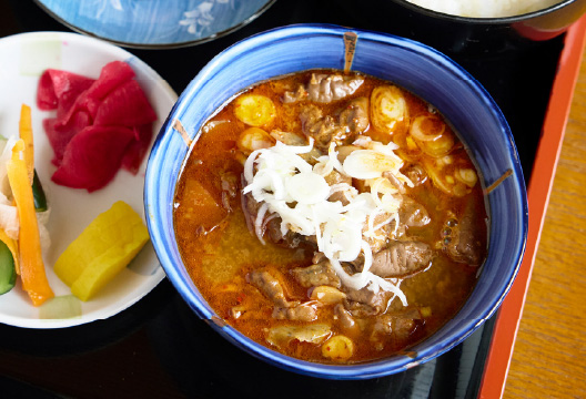 もつ煮込みの入った丼と副菜