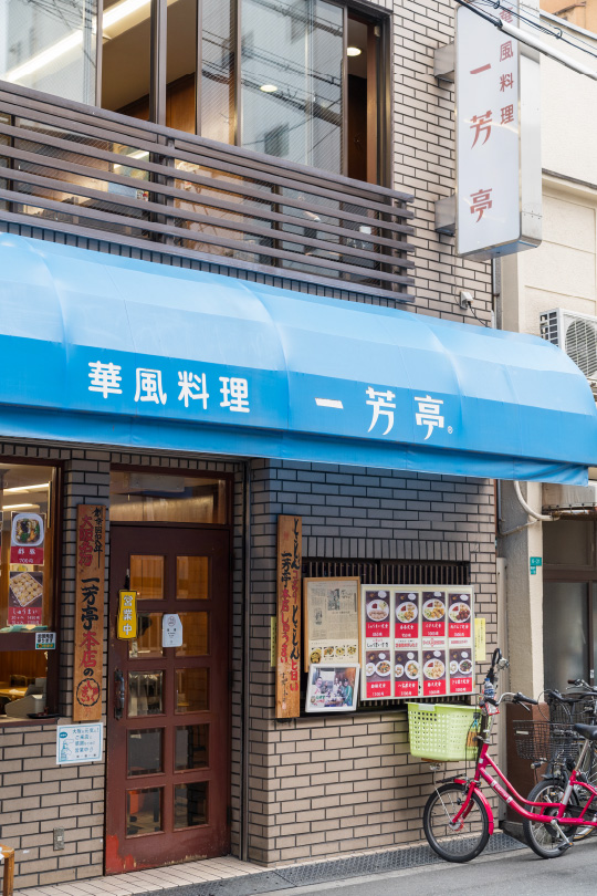 南海難波駅東側すぐの好立地。昭和レトロな建物に青いテントが映え、老舗名店の雰囲気が感じられます