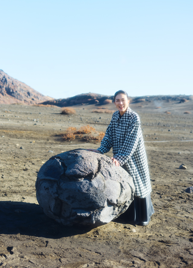 噴火で飛び出したマグマが空中で冷え固まった「火山弾」を前に板谷さんは自然のすごさに感心