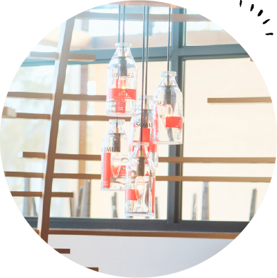 木の質感を生かしたナチュラルな雰囲気の店内。奥の席では900mlの牛乳瓶が照明に使われている