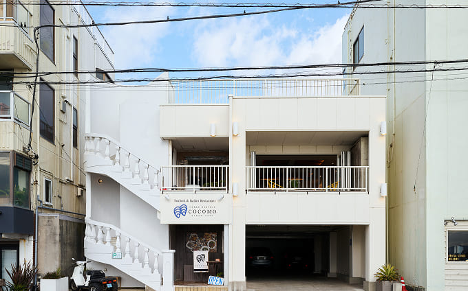 西海岸を思わせる白壁の外観。階段を上がった2階が入口