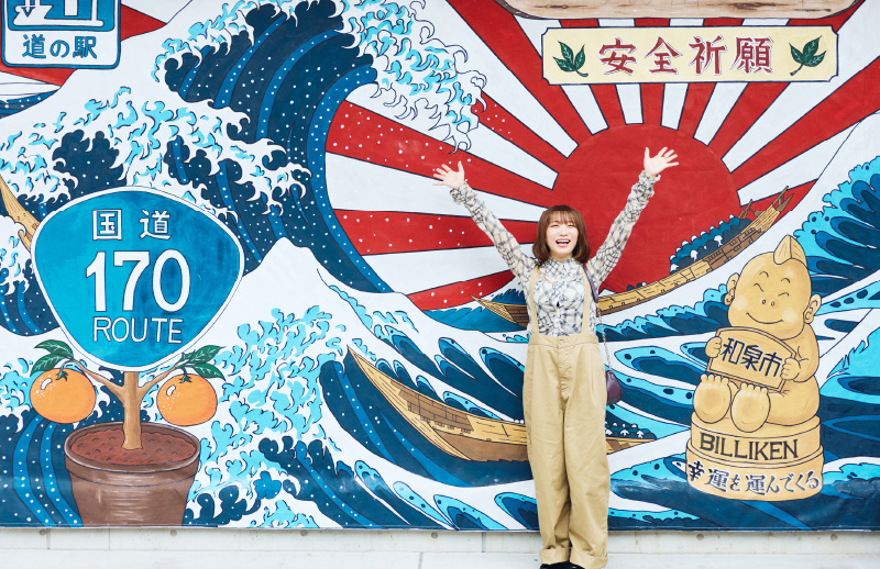 壁画の前で記念撮影をする秋元真夏さん