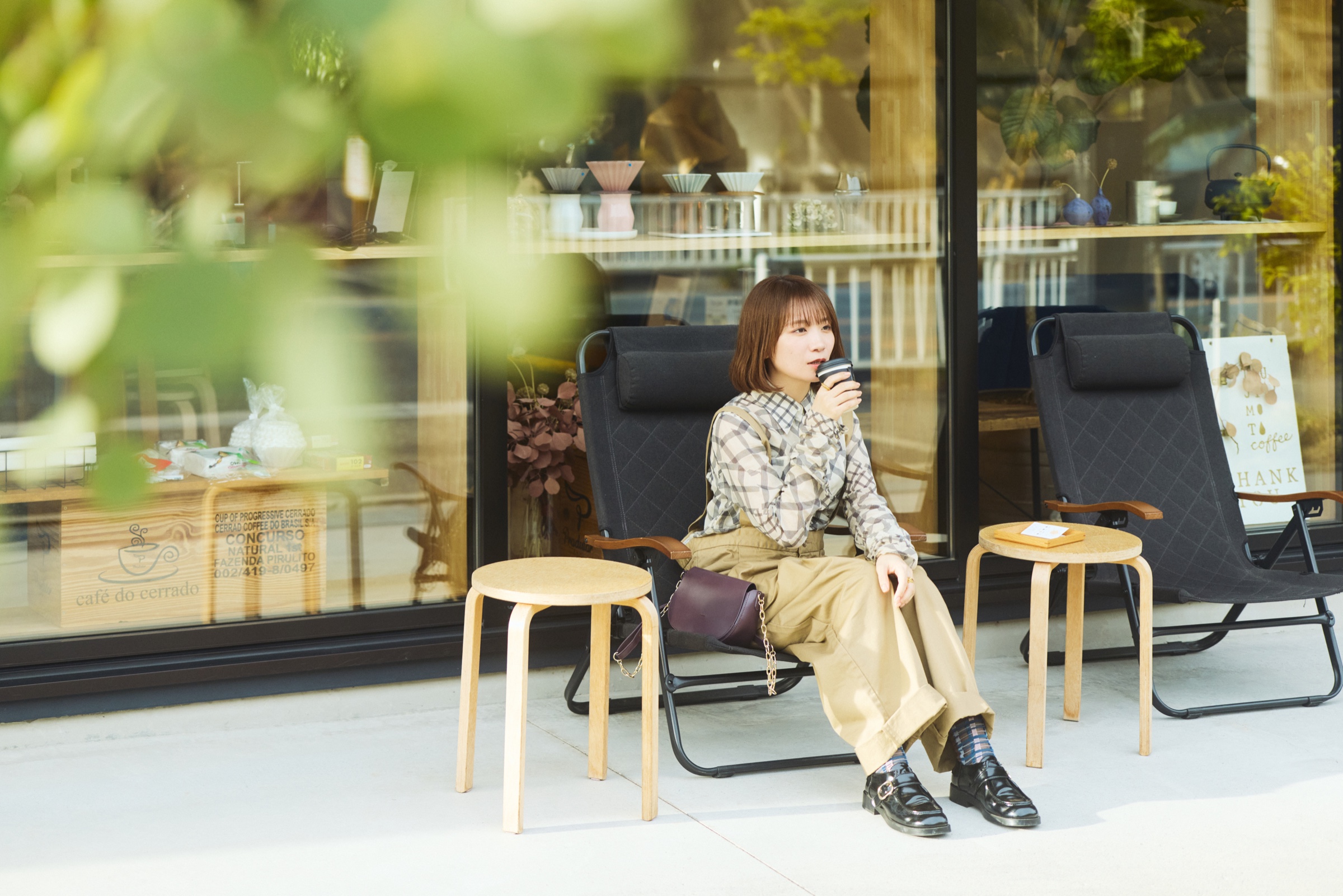 辻󠄀本珈琲の店前でコーヒーを味わう秋元真夏さん